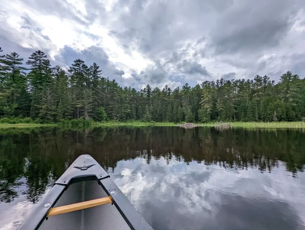 Canoe view of lake in Samuel de Champlain Provincial Park, with mirror reflections of forest ahead