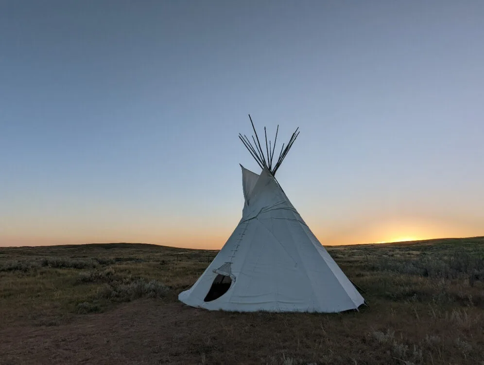 White tipi in front of sunset view in Grasslands National Park
