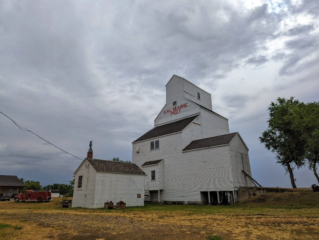 Looking up at white grain elevator, which has the text 'Val Marie 1927' in red lettering near the top