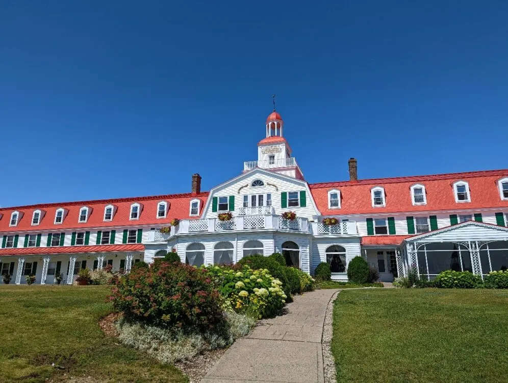 Hotel Tadoussac featuring white and red exterior and large lawn area with colourful flowers