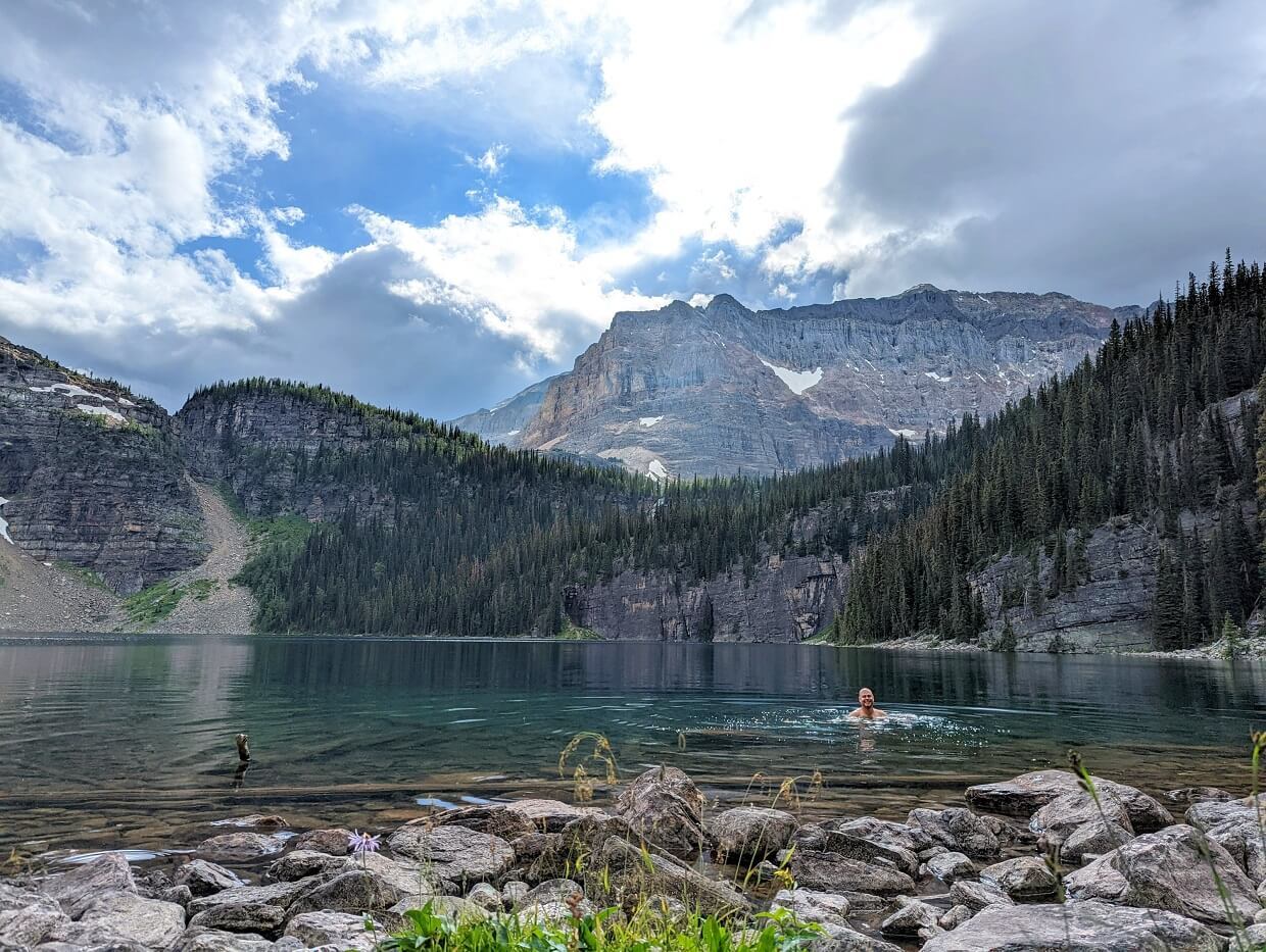 Looking across Egypt Lake, which is backdropped by forest and mountains. JR is swimming in the lake; his head is visible. 