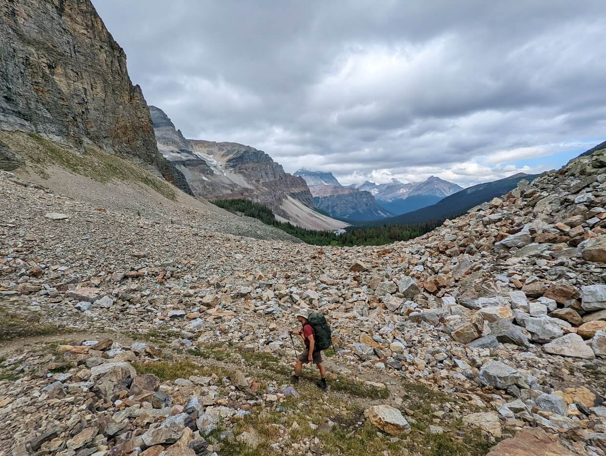 Side view of JR hiking up rocky Whistling Pass trail, with endless mountains in background