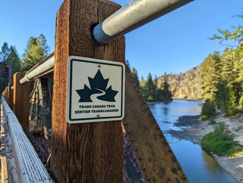 Close up of Trans Canada Trail sign on Kettle River trestle bridge, with river visible in background