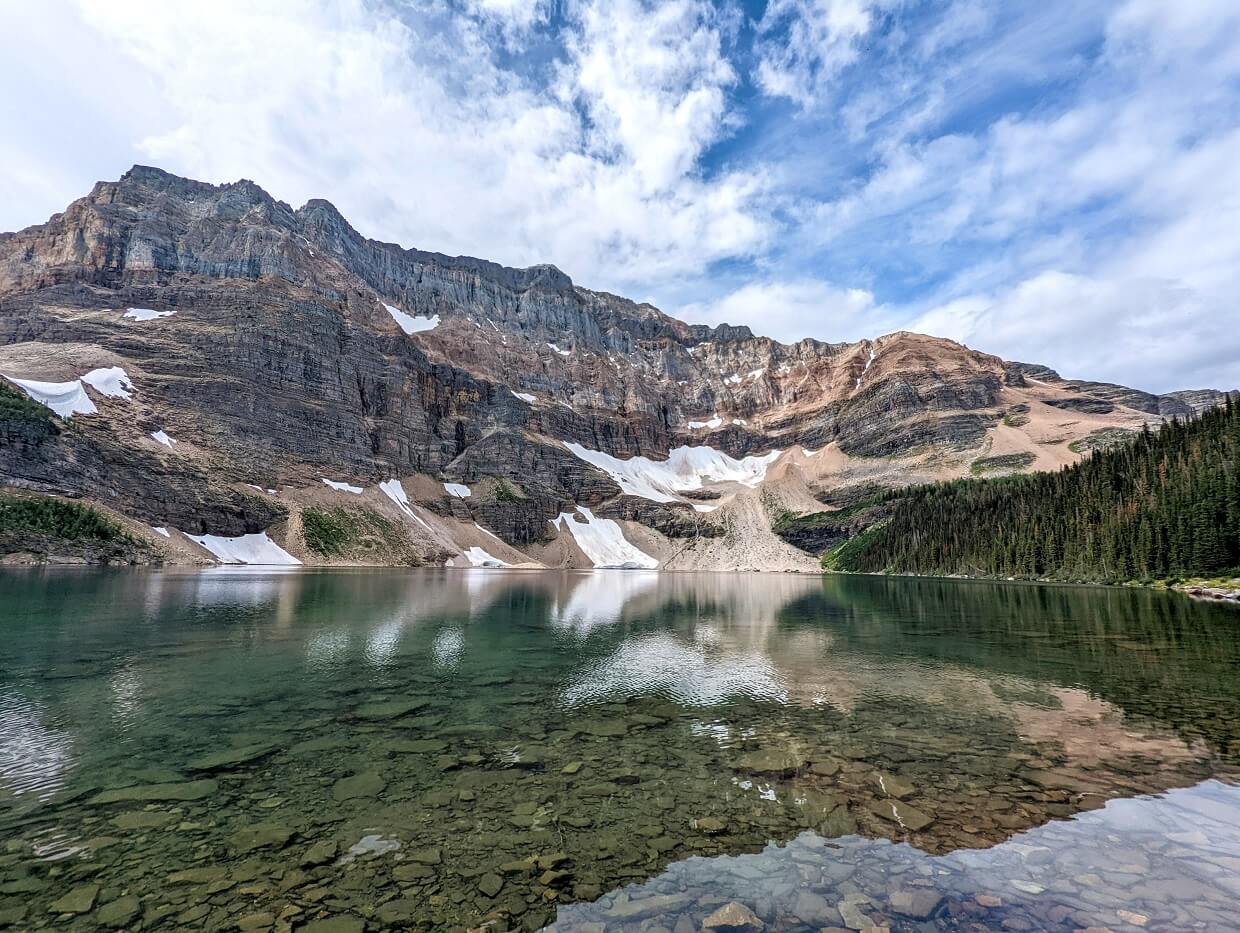 Looking across calm and reflective Scarab Lake, which features a large mountain range behind