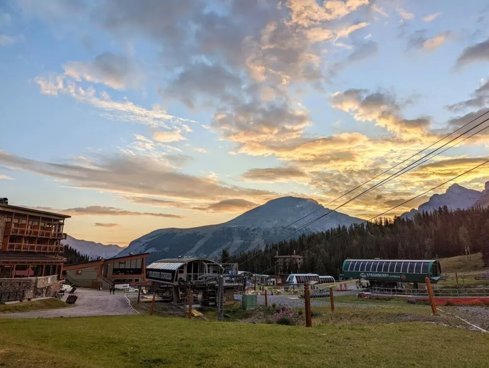 Sunrise over Sunshine Village, with golden clouds over mountains and chairlift, with hotel building visible on left