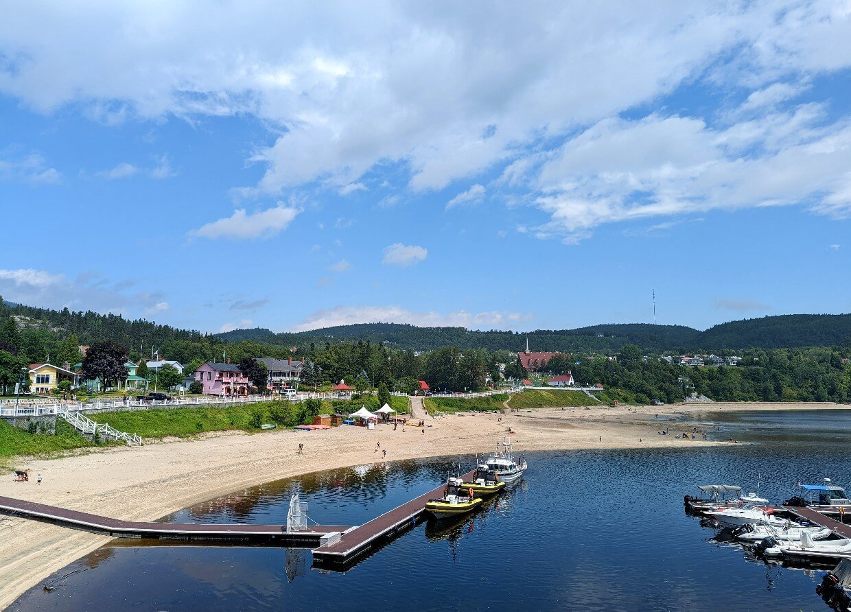 Elevated view from marina looking across Tadoussac Bay, which features a golden sand beach backed by promenade