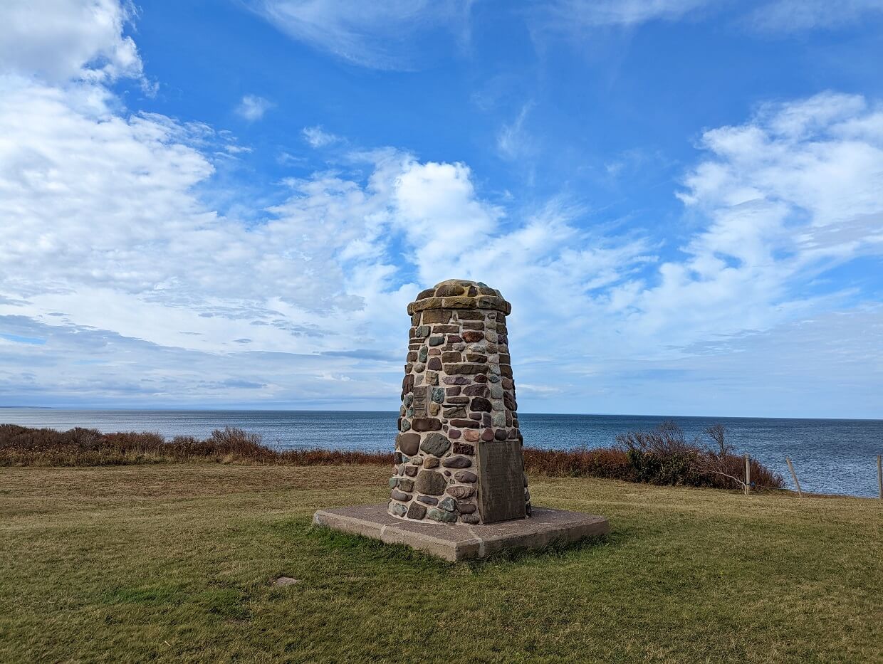 Stone Culloden Memorial surrounded by grass in front of ocean on Cape George Scenic Drive