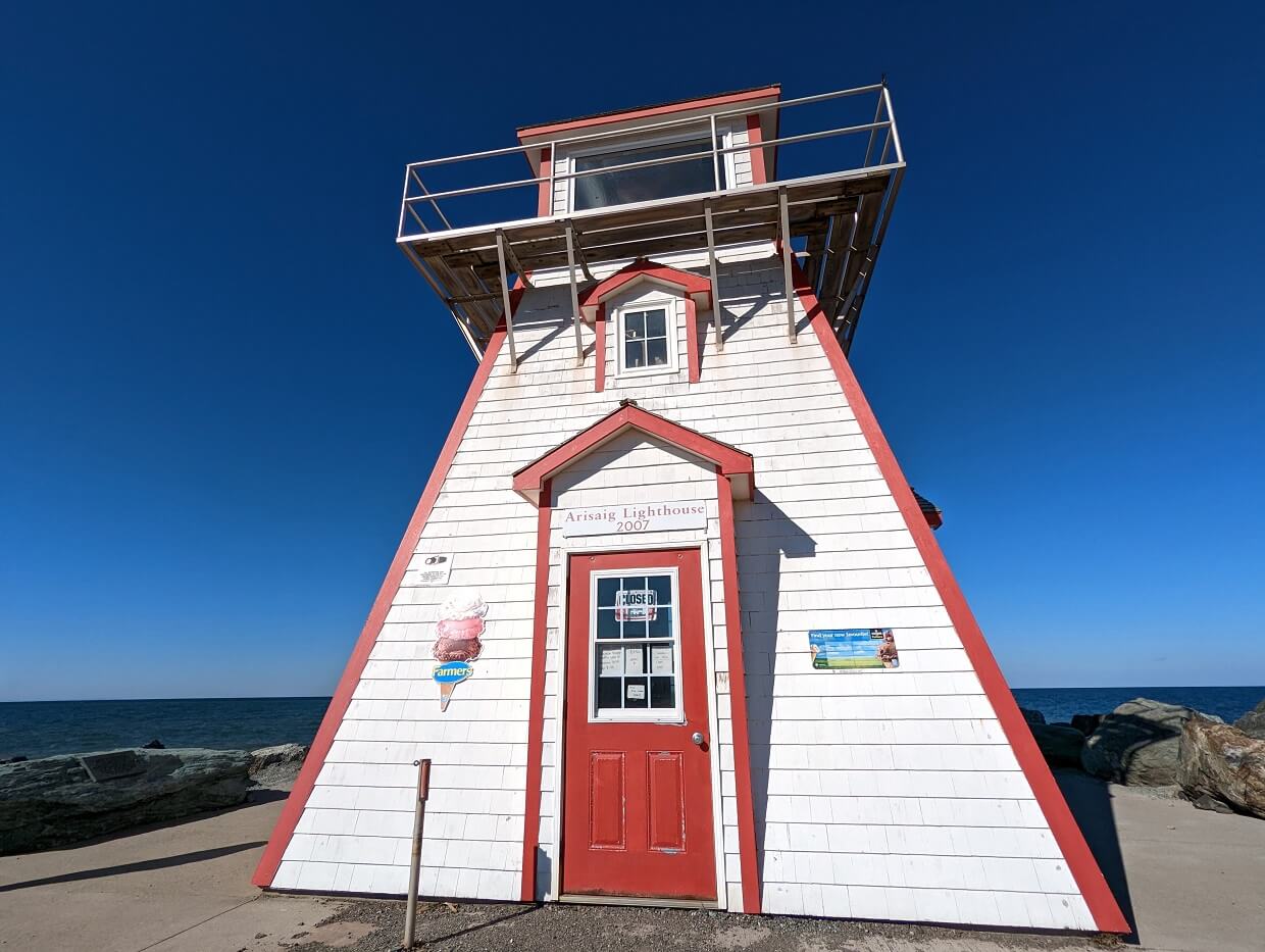 Arisaig Lighthouse, a squat red and white building with ice cream signage in front of ocean