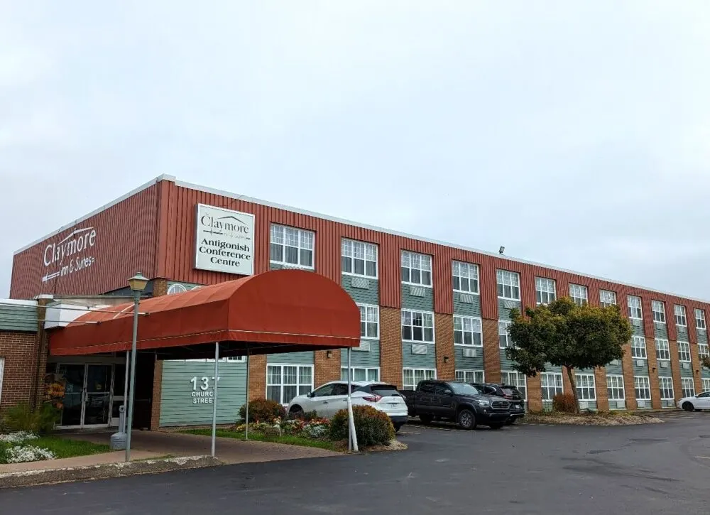 Exterior view of three story Claymore Inn and Suites building, with parking lot