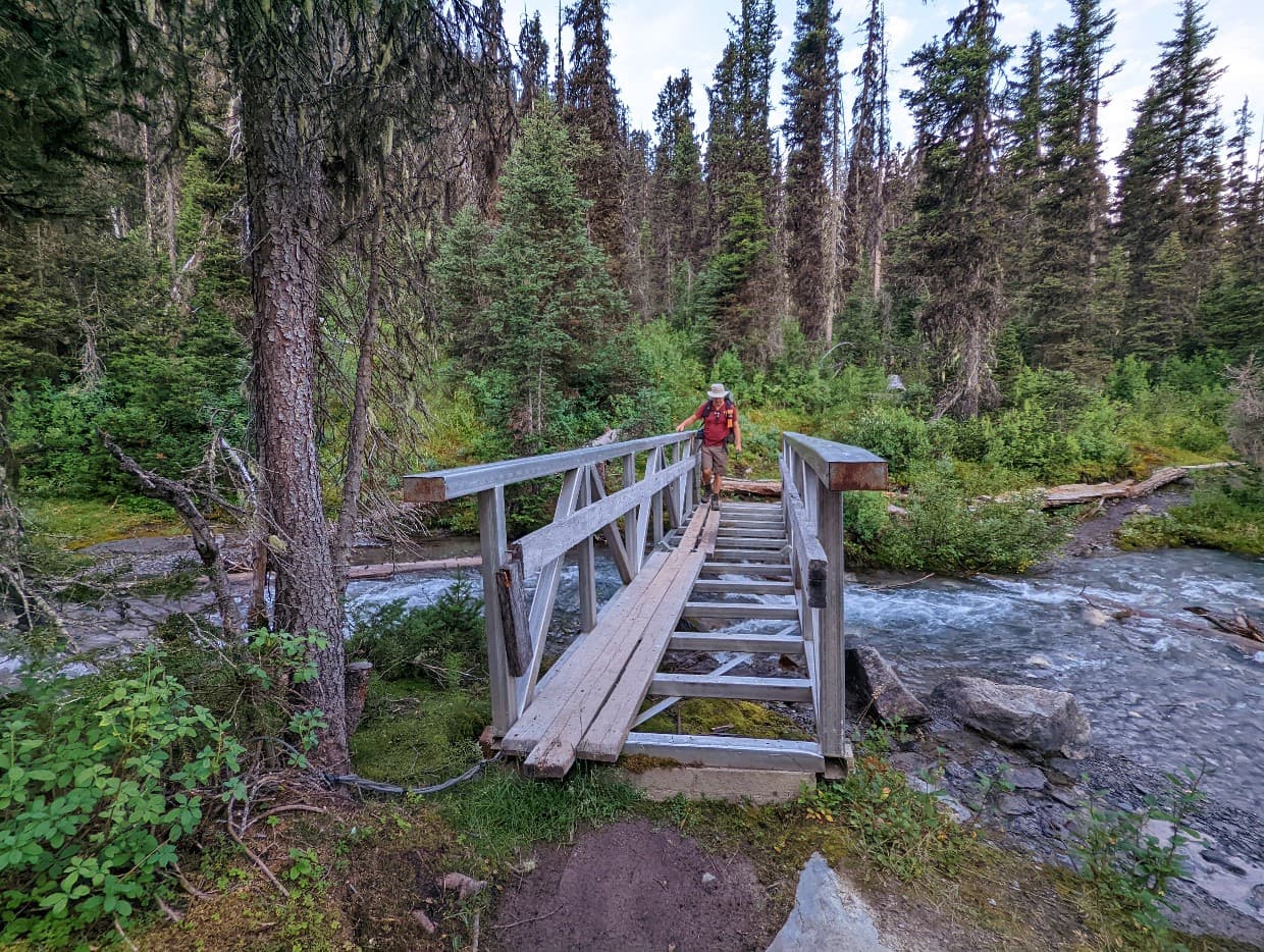 JR is crossing a damaged bridge - it is missing most of the planks of wood