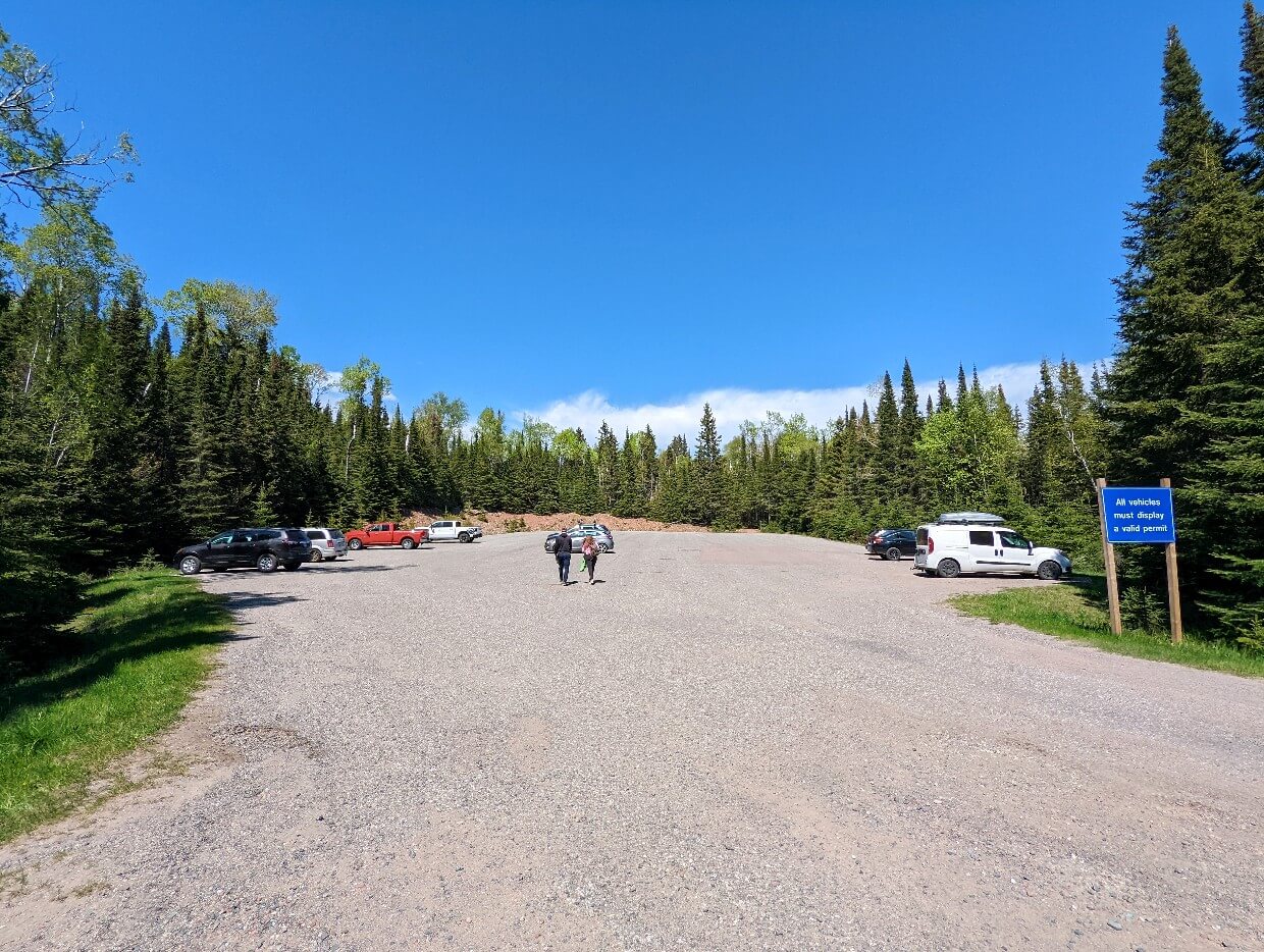 Looking towards huge dirt parking lot with half a dozen vehicles parked (South Kabeyun Trail)