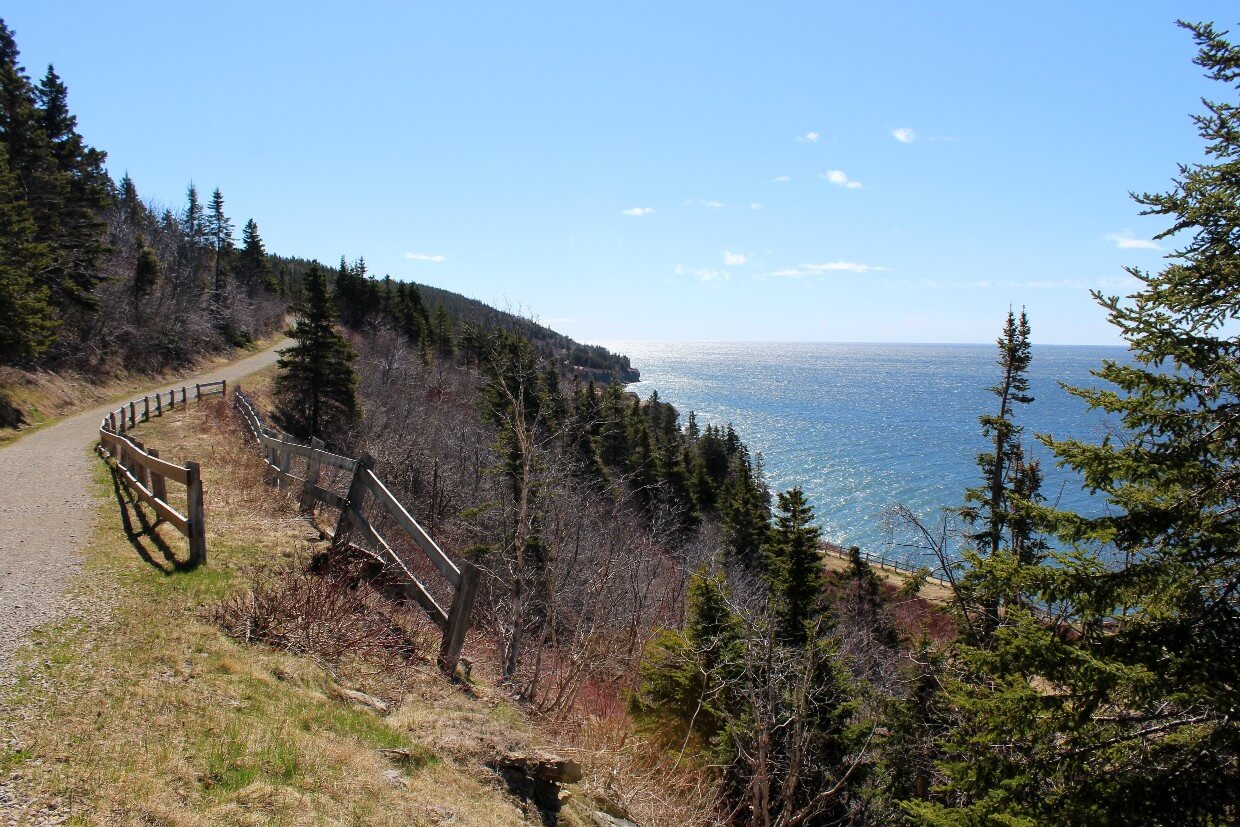 Wide hiking trail leads away from camera on left, following the coastline in Forillon National Park