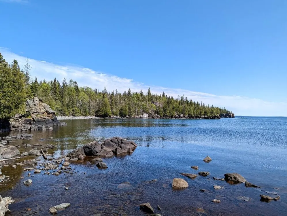 Looking across calm bay of Lake Superior, with boreal forest bordering shoreline