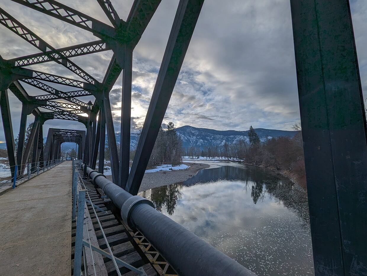 Looking through the metal struts of the Black Train Bridge in Grand Forks, to the reflective Kettle River below