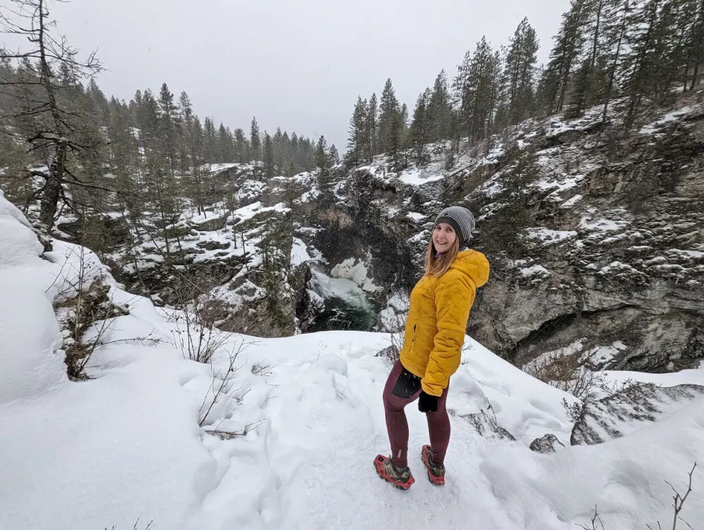 Back view of Gemma in yellow jacket in front of gorge, with Cascade Falls visible in background