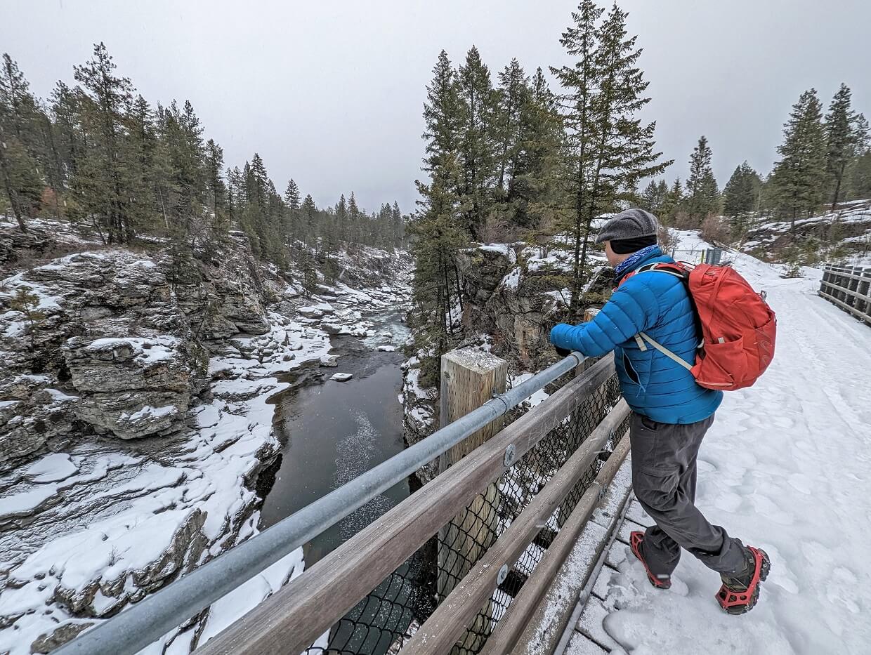Side view of JR leaning on wooden siding on trestle bridge in Cascade Gorge , with steep snowy canyon below