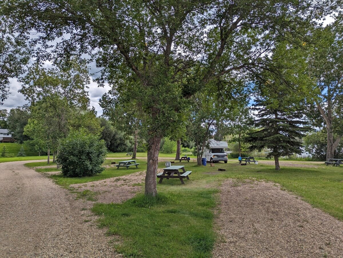 Alix Campground campsites with dirt pad areas next to picnic tables. Trees provide shade overhead
