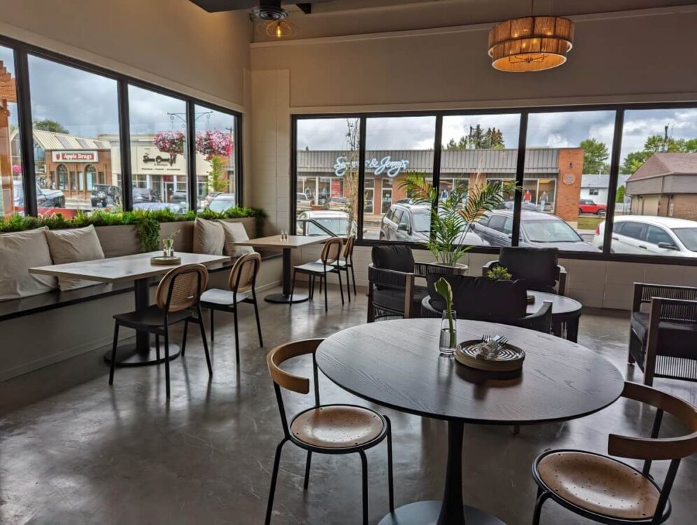 Empty Oaklynn and Vine bistro with large, bright corner windows and minimalist furniture