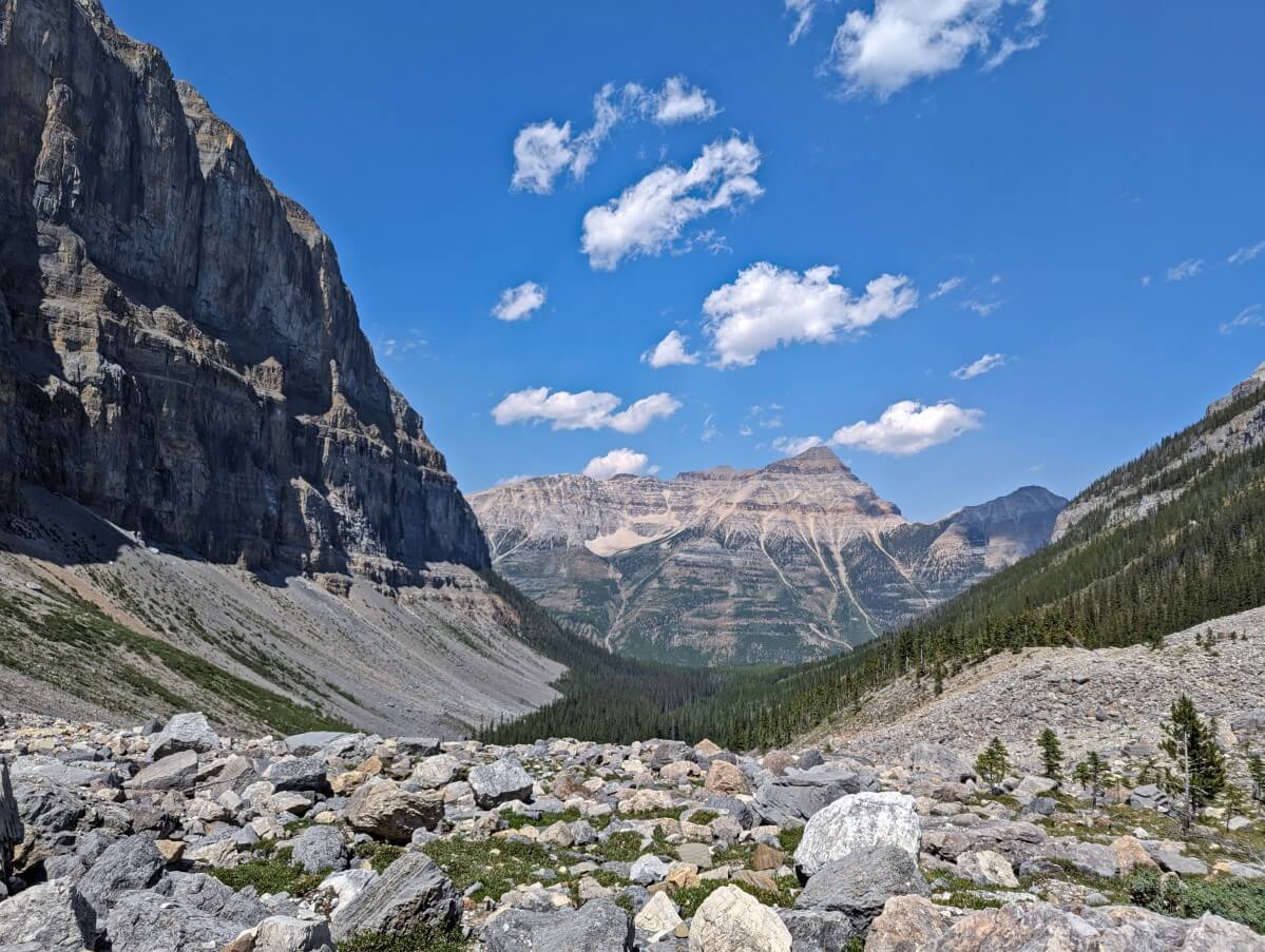 Rocky terrain ahead with steep cliffs rising on left and large mountain in background