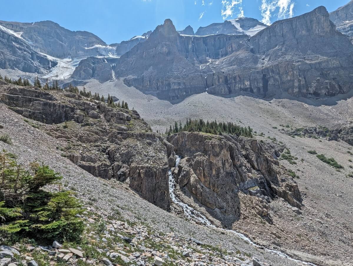 Looking across to waterfall cascading through small canyon with glacier above