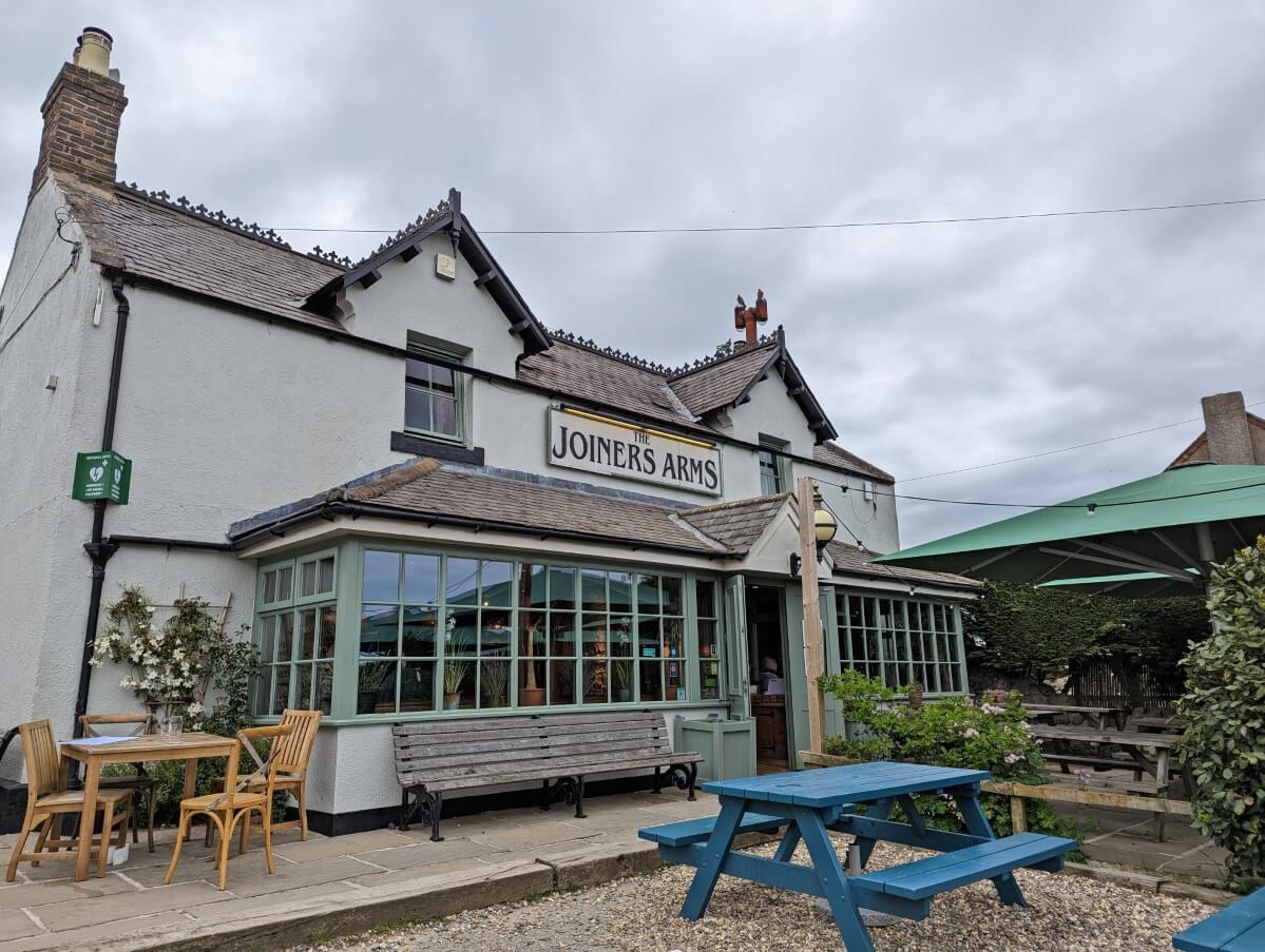 Joiners Arms pub in High Newton, a white two storey building with patio seating in front