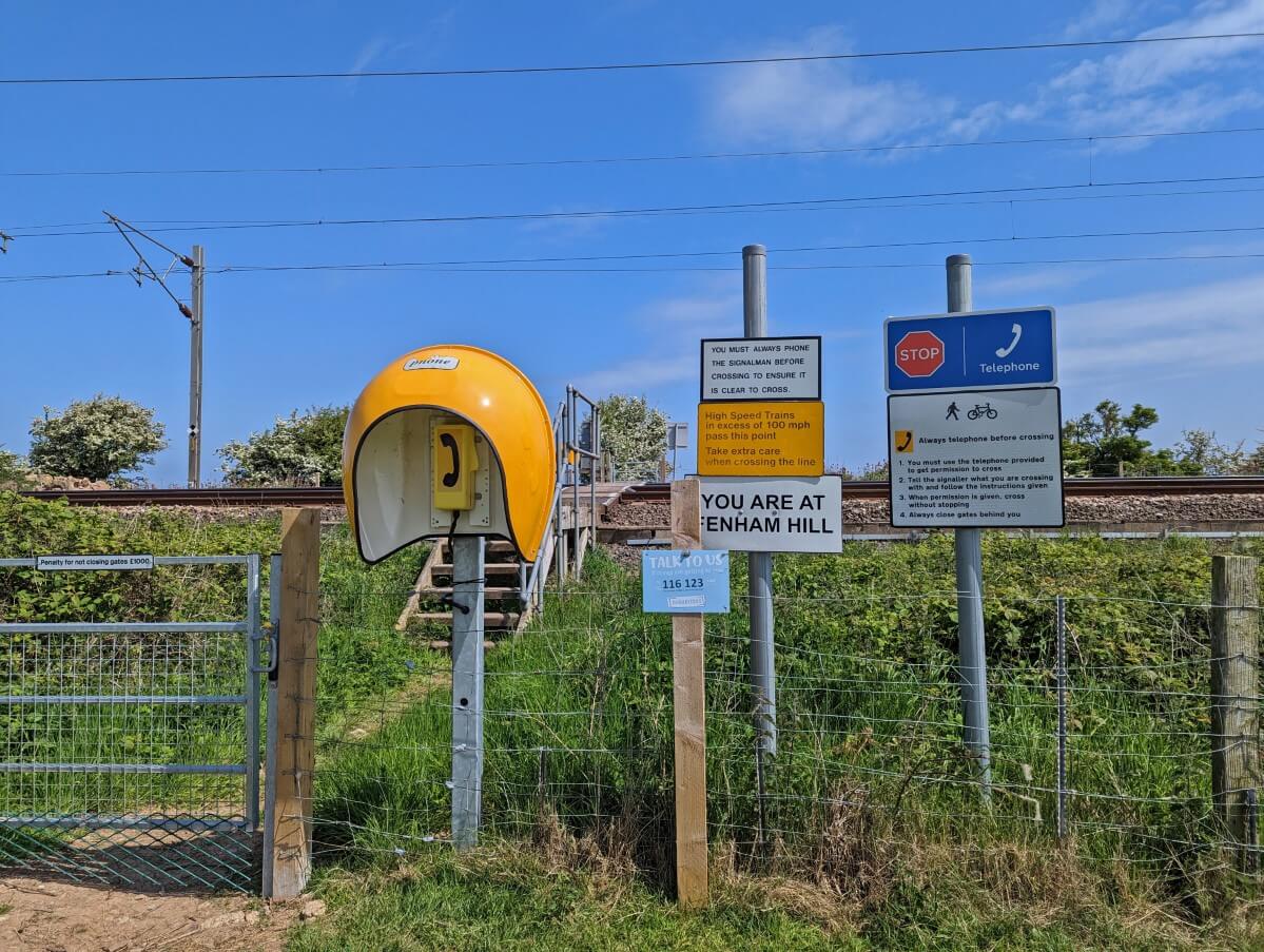 Signage and telephone box on side of railway line on Northumberland Coast Path