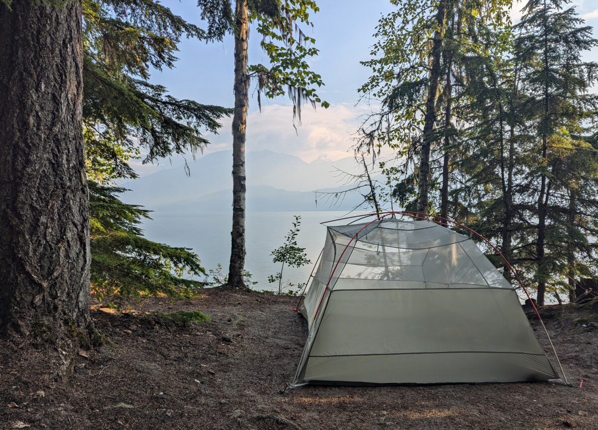 Set up inner tent in forested campground with views of calm lake