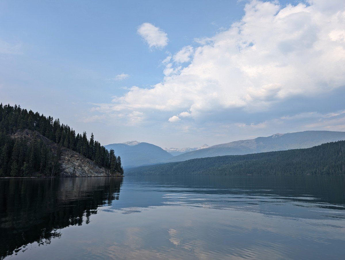 Calm, mirror like Clearwater Lake with cliffs on left and forested mountains on right