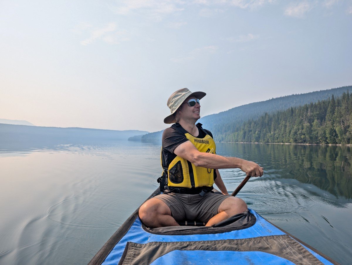 First paddler view looking back to rear paddler on calm lake, with slightly smoky skies