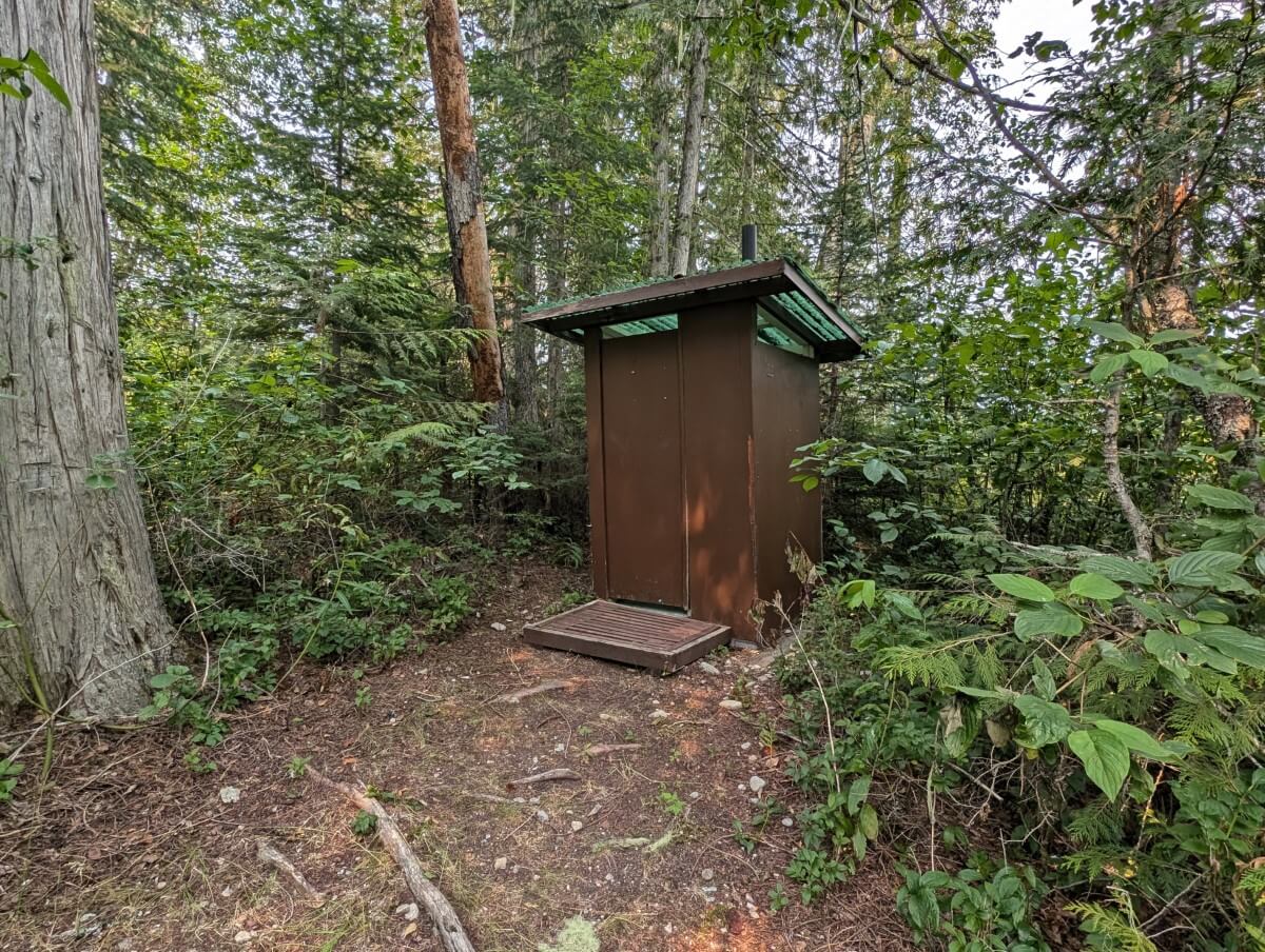 Forested campground view of wooden vault (pit) outhouse