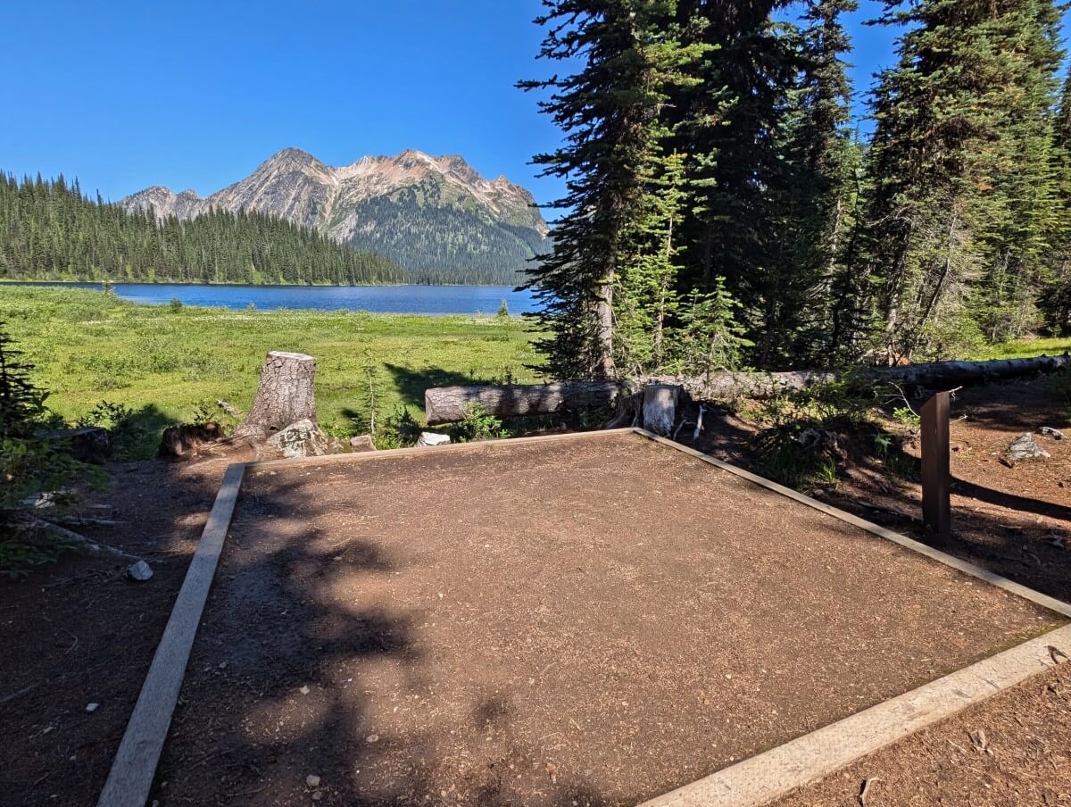 Dirt framed tent pad at Big Peters Lake Campground, with forest on right hand side