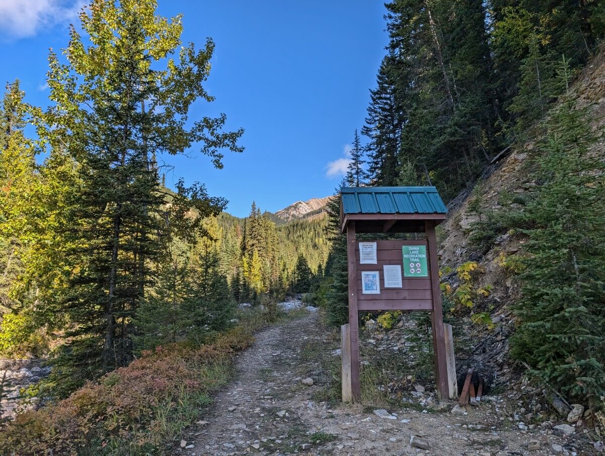 Looking up at the Diana Lake info kiosk at the trailhead, with the actual dirt trail on the left, leading into the distance
