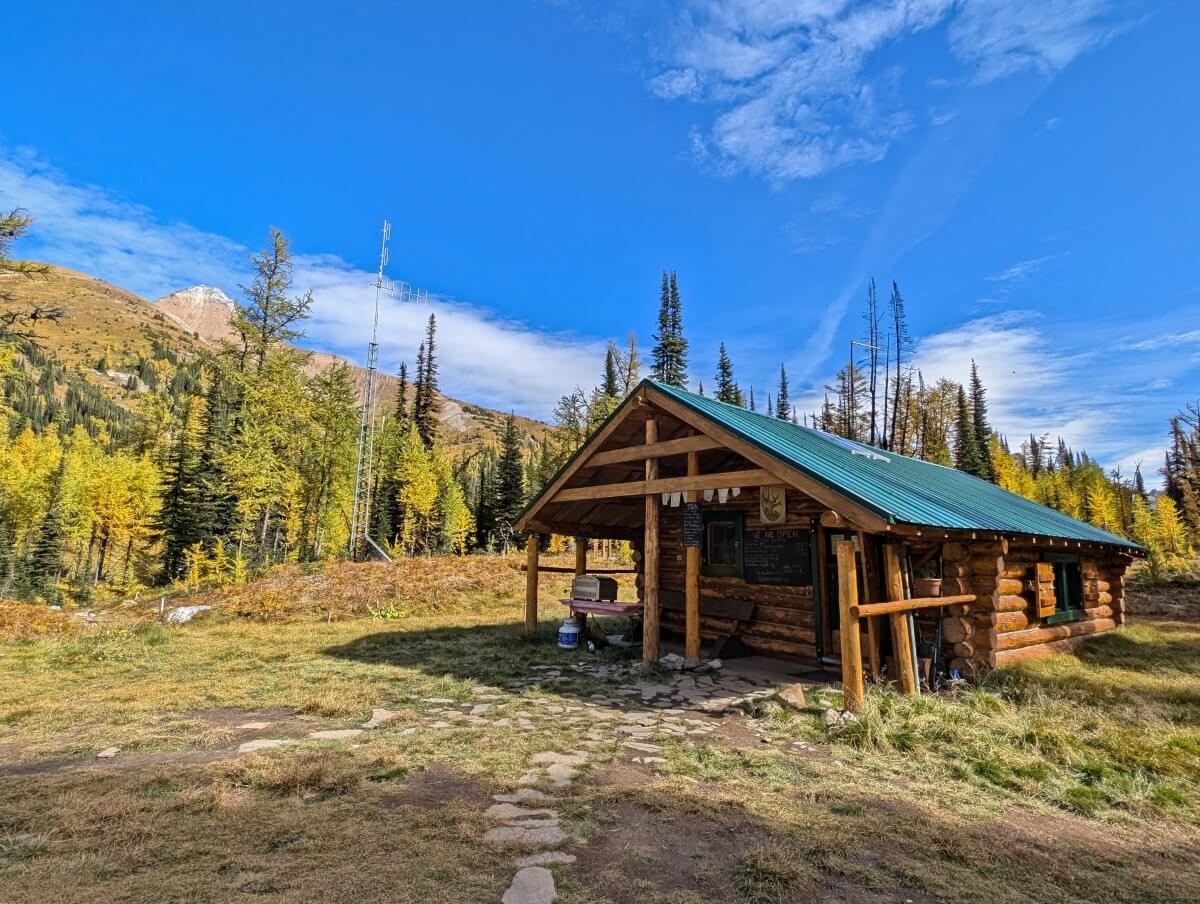 The main cabin at Diana Lake Lodge, a log cabin building with green/blue roof in meadow clearing in sub-alpine environment
