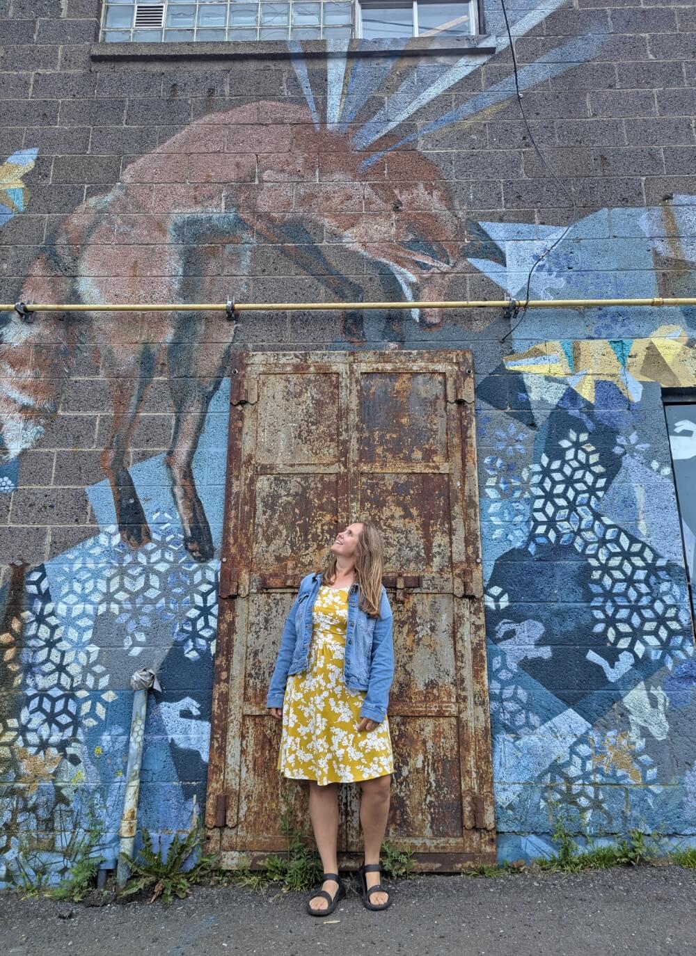 Gemma stands in front of street art featuring a fox in Thunder Bay