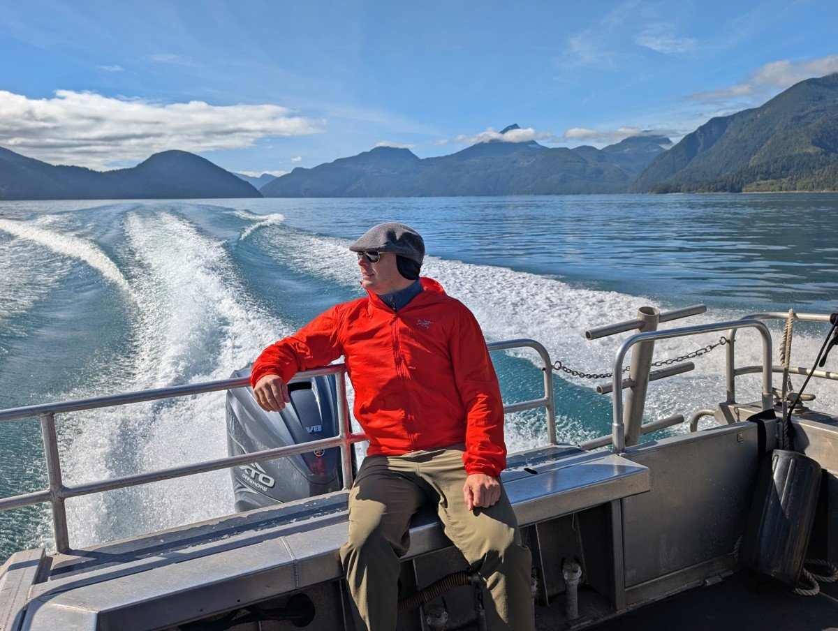 JR sits on the back of the boat in Bute Inlet, checking out the views of the surrounding forested mountains