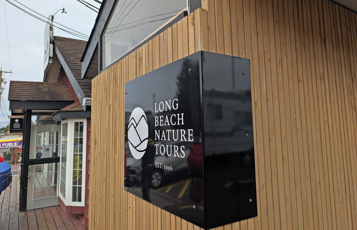 Close up of black and white Long Beach Nature Tours logo outside office in Tofino