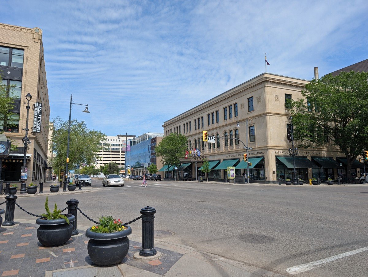 Downtown Saskatoon street scene from sidewalk, featuring early 20th century style buildings in light stone