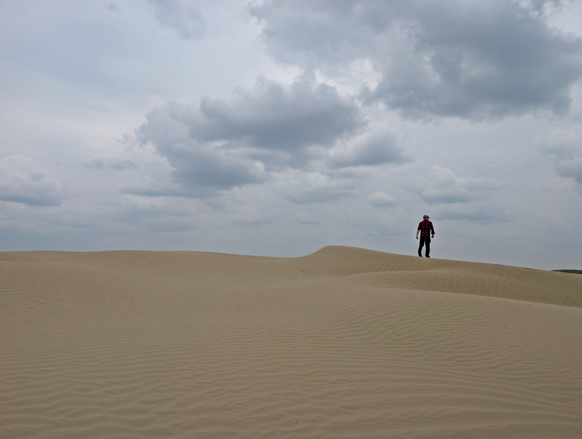 Back view of JR standing on top of large sand dune at the Great Sand Hills in Saskatchewan