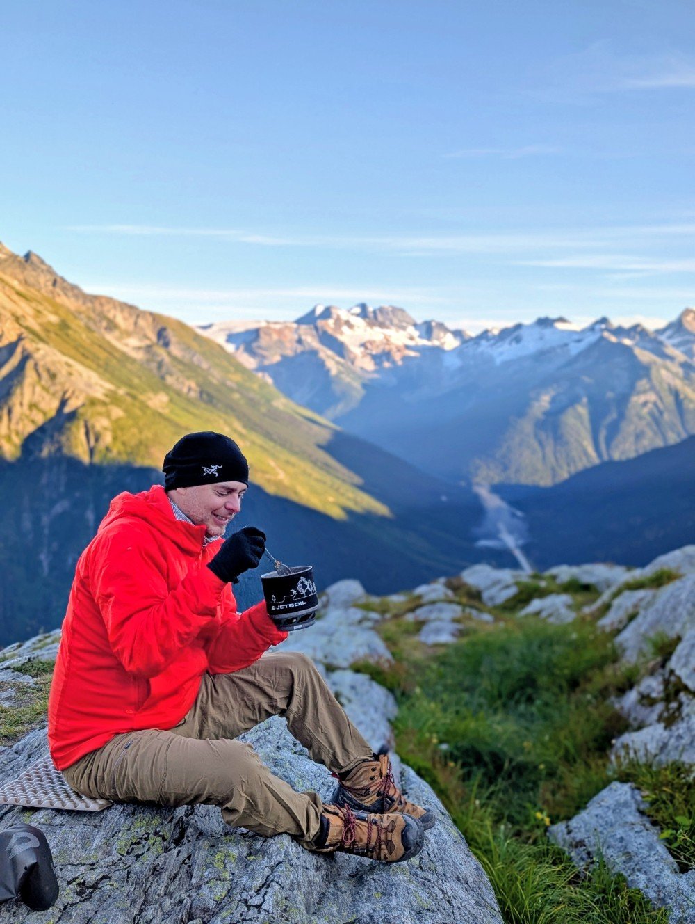 Close up of JR eating food from Jetboil pot, with blurred mountain background