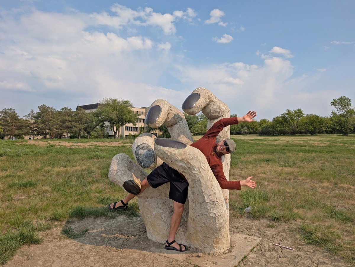 JR stands in the middle of the hand sculpture in the sculpture garden at the University of Saskatchewan