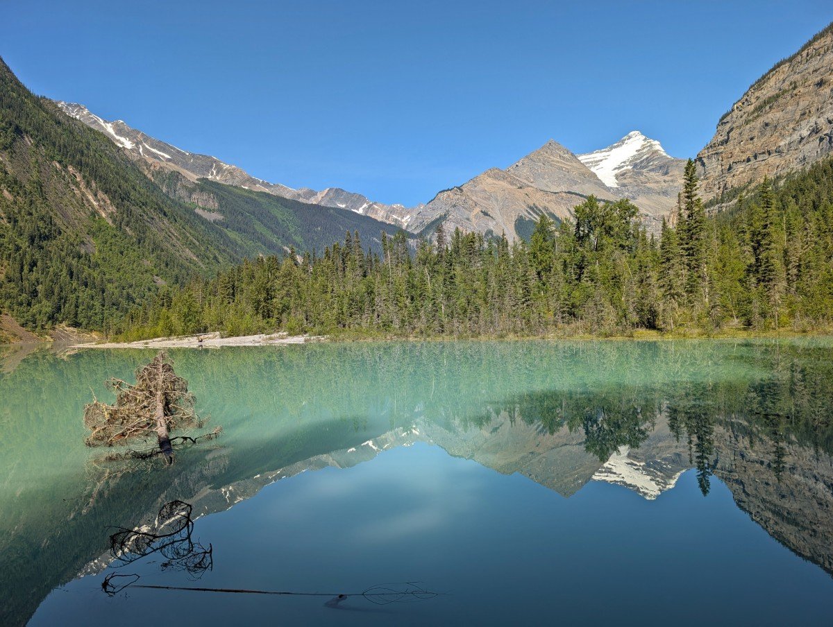 View of Kinney Lake, a calm lake reflecting the steep mountains behind it