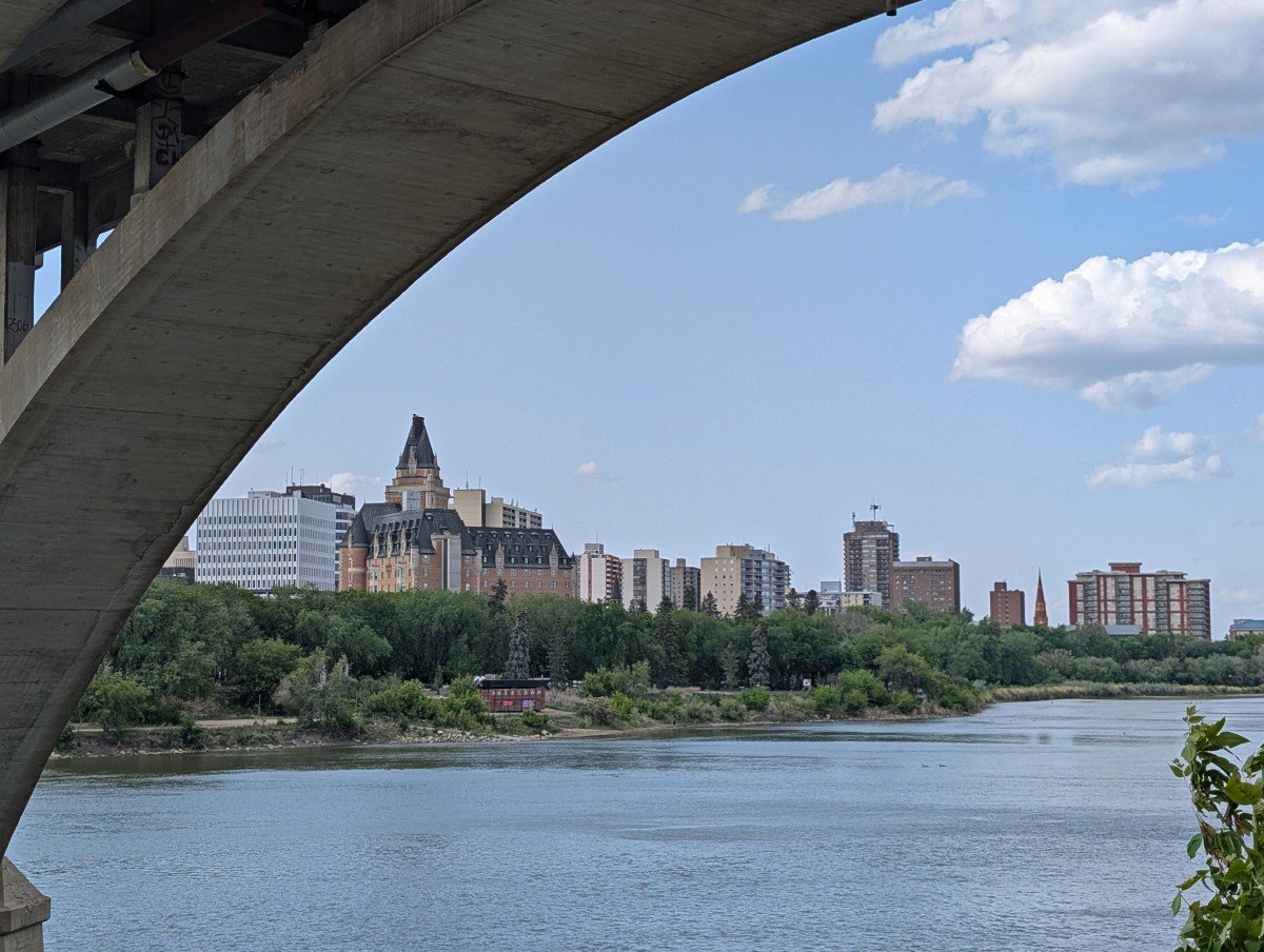 Under bridge view of the South Saskatchewan River and downtown Saskatoon looking towards the castle-like Bessborough hotel