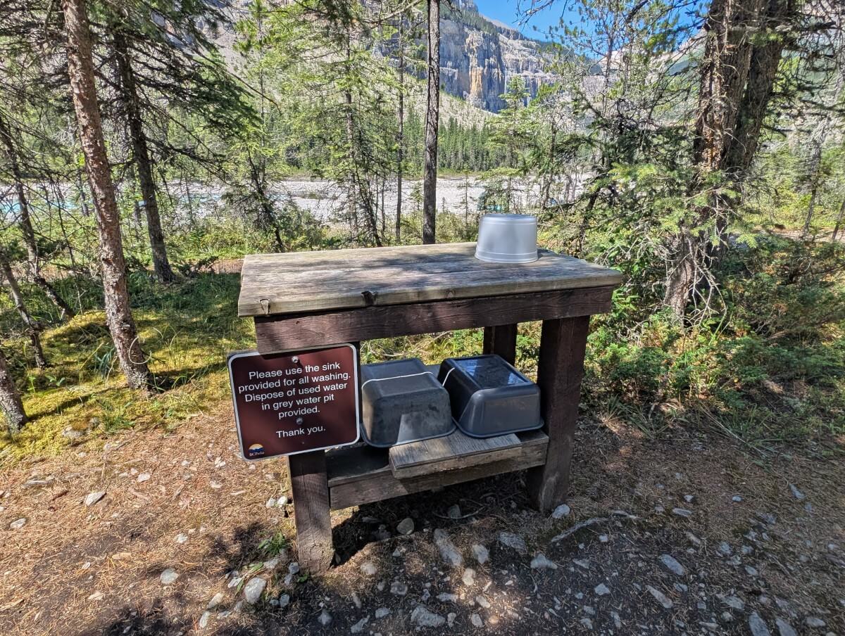 Close up of dish washing station at Berg Lake Campground, featuring a two level wooden table and washing up bowls