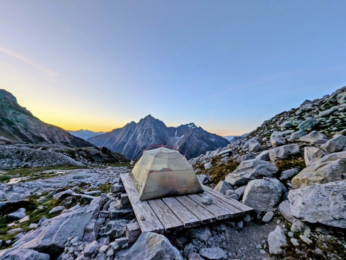 Set up interior of tent on wooden platform at Hermit Meadows campground, surrounded by rocks, with a mountainous background