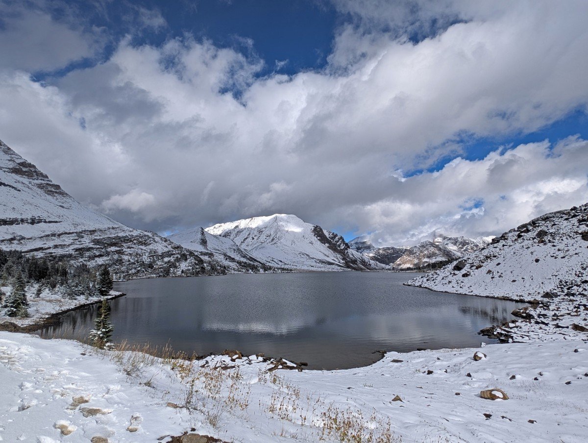 Ptamigan Lake, as seen after Boulder Pass, surrounded by a snow covered rocky and mountainous backdrop