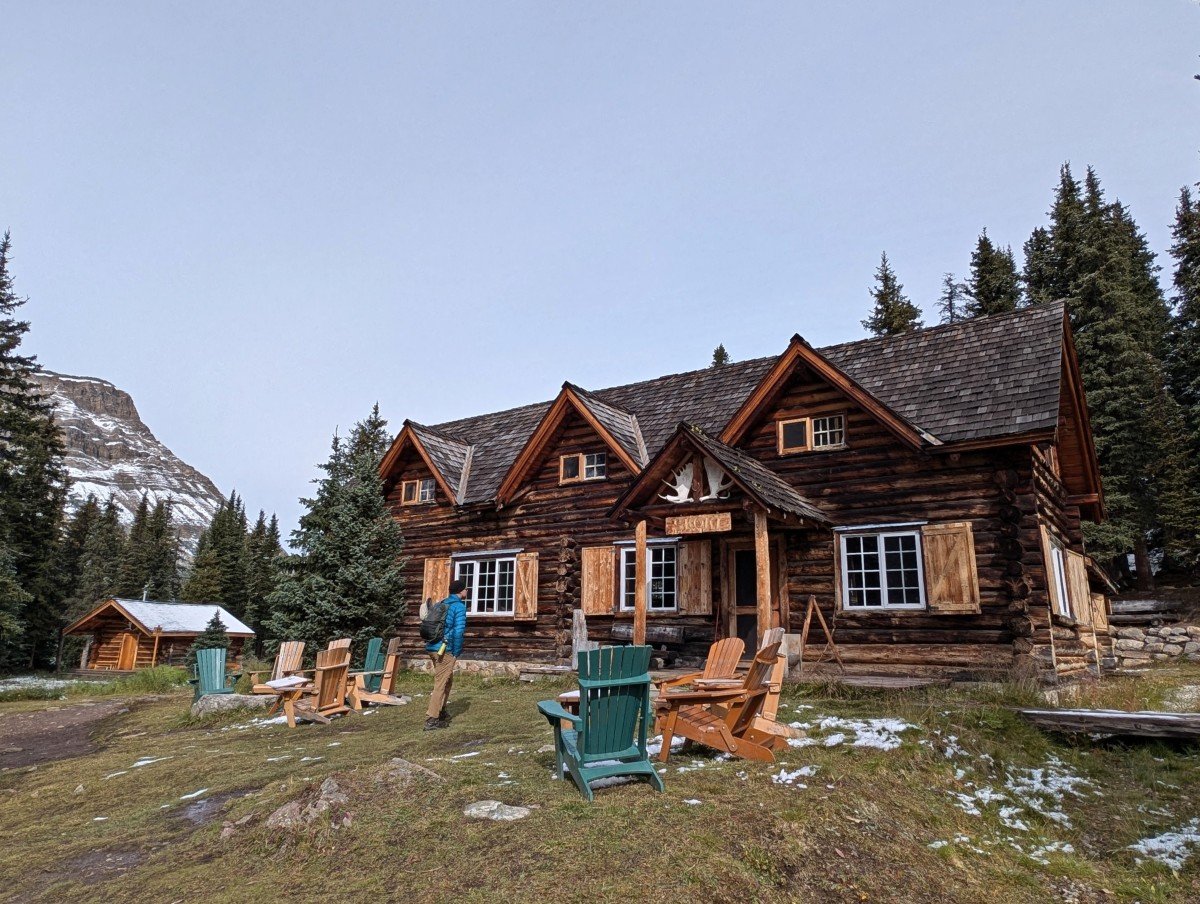 Historic Skoki Lodge, a two floor wooden cabin-like building in mountainous location with collection of adirondack chairs set in front