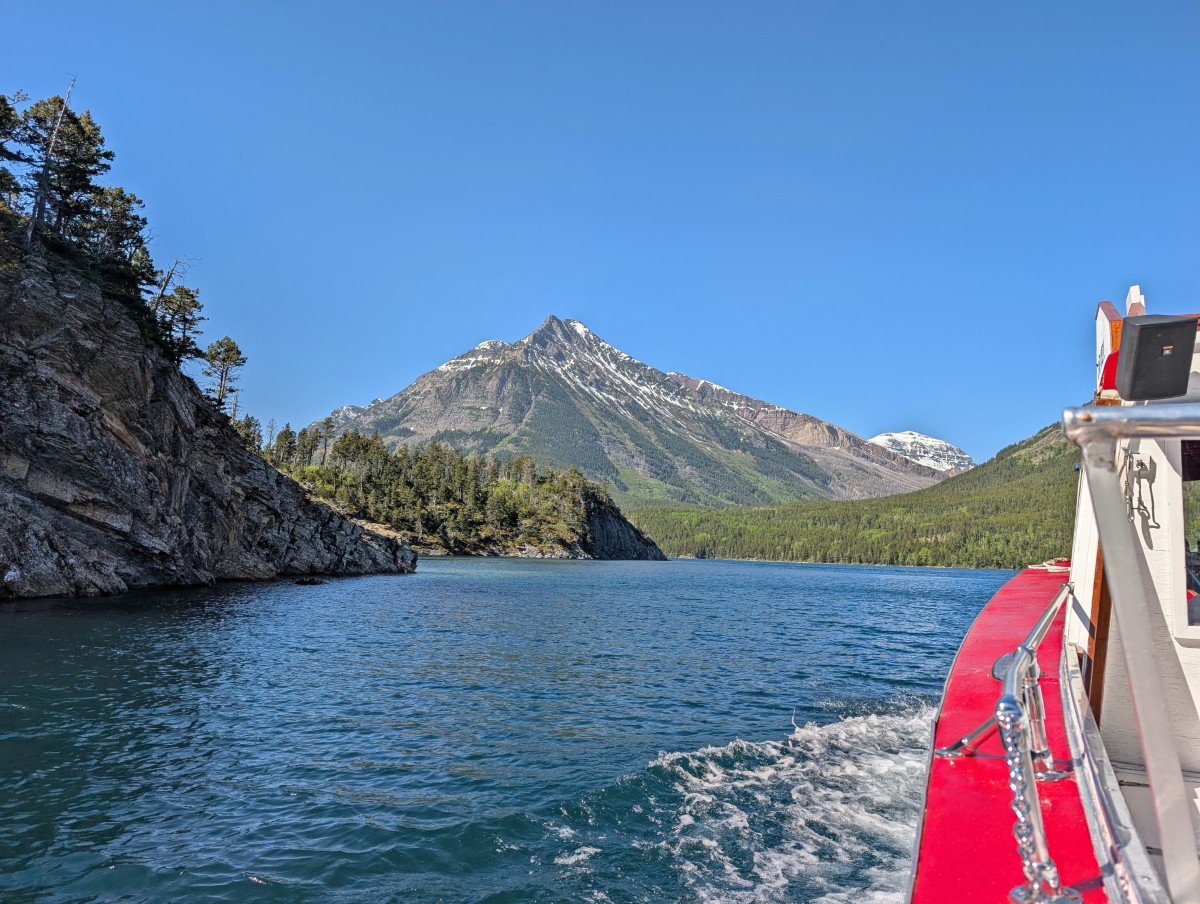 Lake and mountain views from boat cruise on Upper Waterton Lake, featuring white and red edge of boat on right