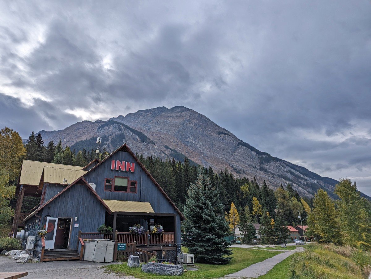 A blue painted two storey building sits with a backdrop of mountains in Yoho National Park (Truffle Pigs)