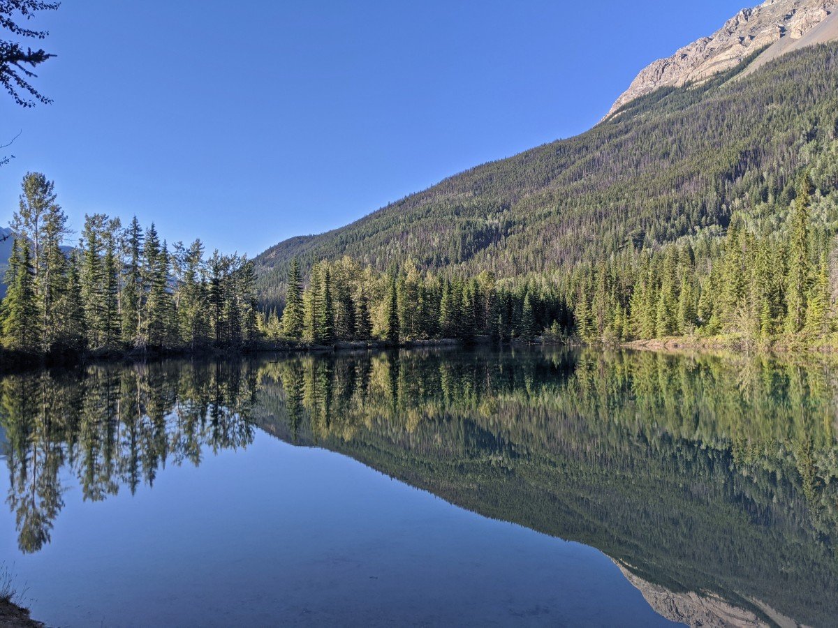 Faeder Lake, a beautiful mirror lake effect on the water, surrounded by trees and with mountain backdrop