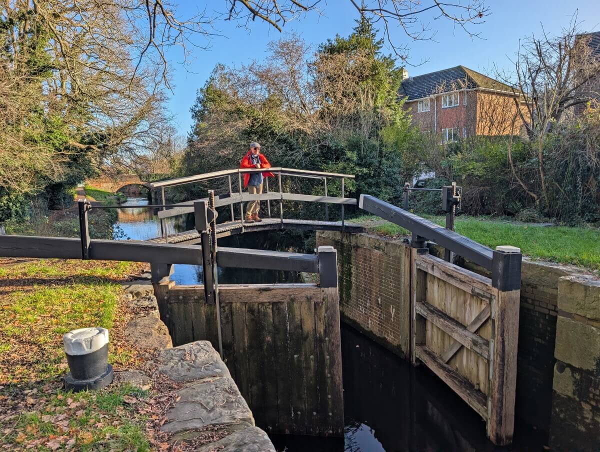 Close up of lock on the Basingstoke Canal, with man standing on the bridge above the open doors